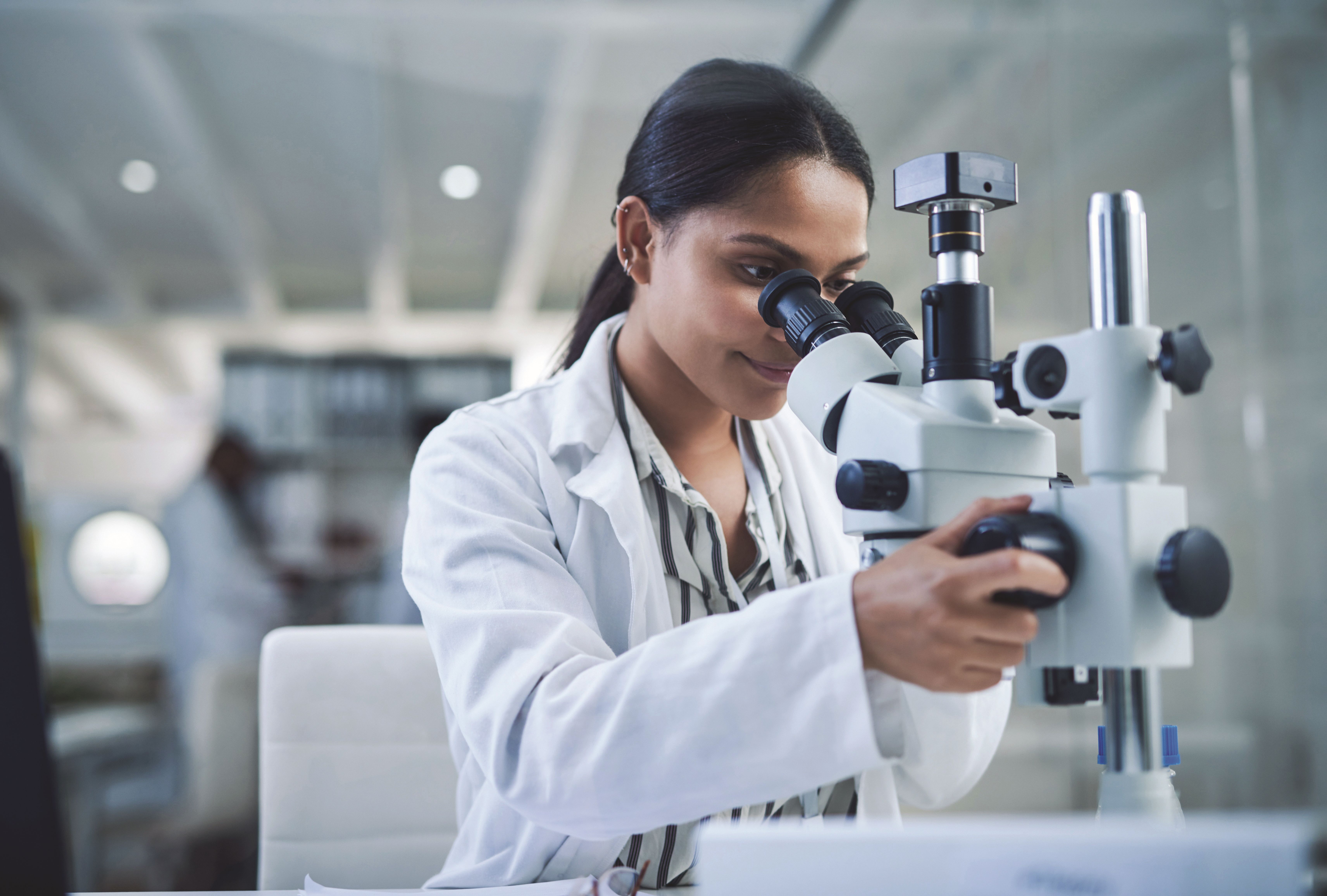Lady looking through microscope.